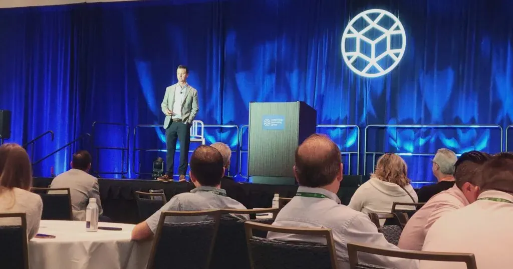 Man presenting on stage at a conference